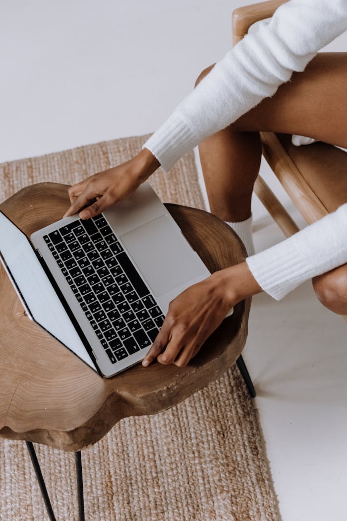 Close-up of a woman typing on a laptop indoors, focusing on technology and modern lifestyle.